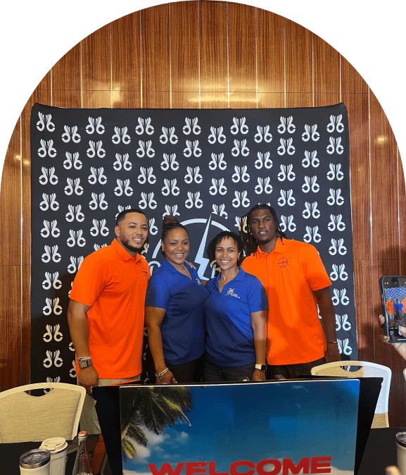 Four people smiling in front of a branded backdrop at an event.