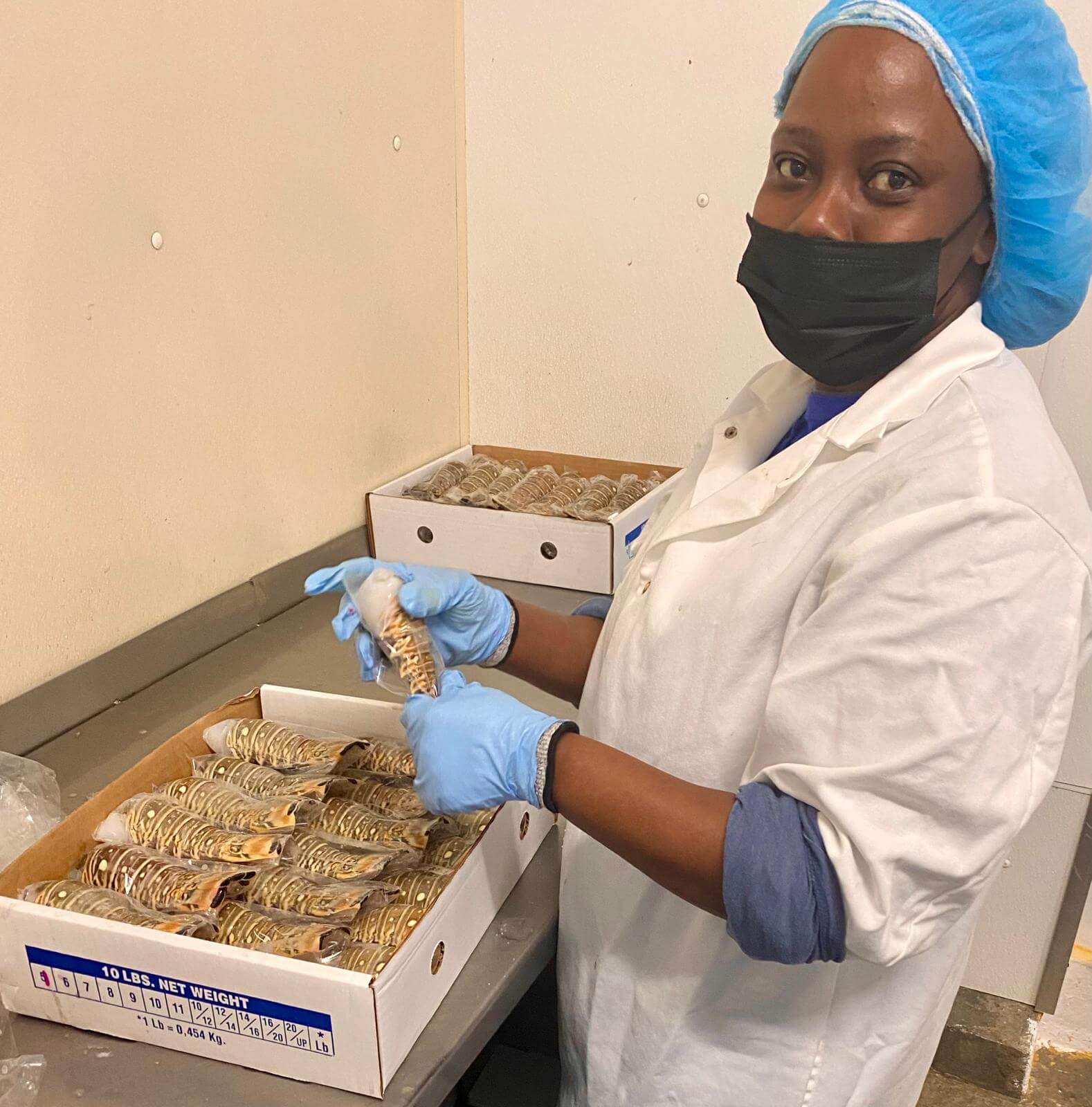 A person in protective gear handling packaged food in a facility.