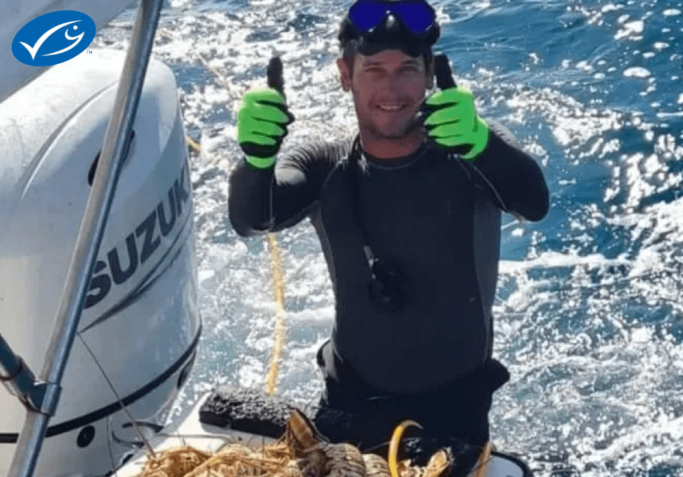 Diver shows a sea creature on a boat with thumbs up.